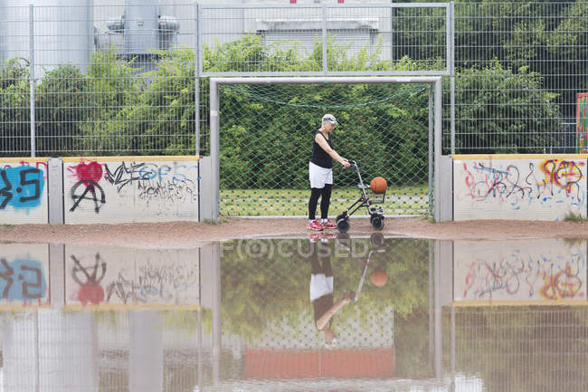 Senior woman with wheeled walker on sports ground — Stock Photo