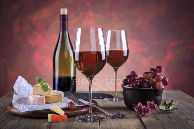 Still life with wine bottle, wine glasses, cheese and grapes — Stock Photo