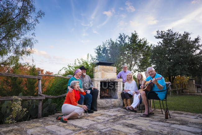 Група людей з гітарою, сидячи в каміні в сільській місцевості — стокове фото