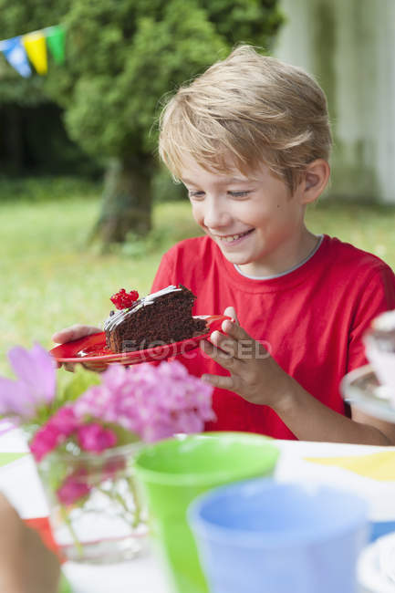 Glücklicher Junge mit Teller und Kuchen auf einer Geburtstagsfeier — Stockfoto