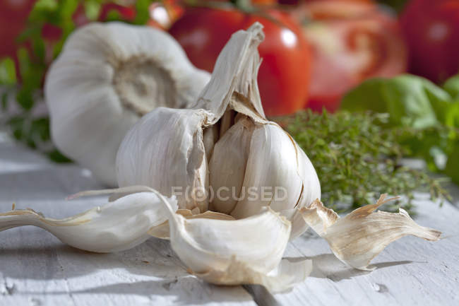 Close up of garlic and herbs on table with vegetables — Stock Photo