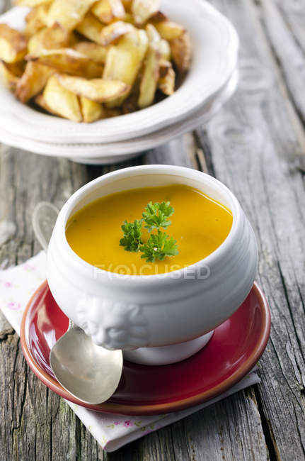 Creamed pumpkin soup in bowl with potato wedges — Stock Photo