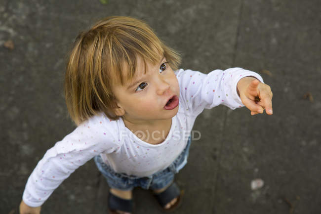 Portrait of cute little girl pointing at something — Stock Photo