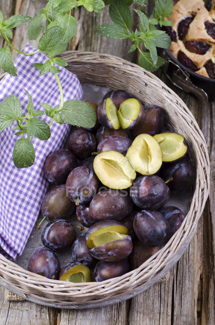 Panier de prunes fraîches sur table rurale en bois — Photo de stock