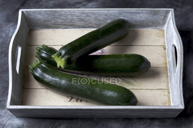 Three fresh Zucchinis on wooden tray — Stock Photo