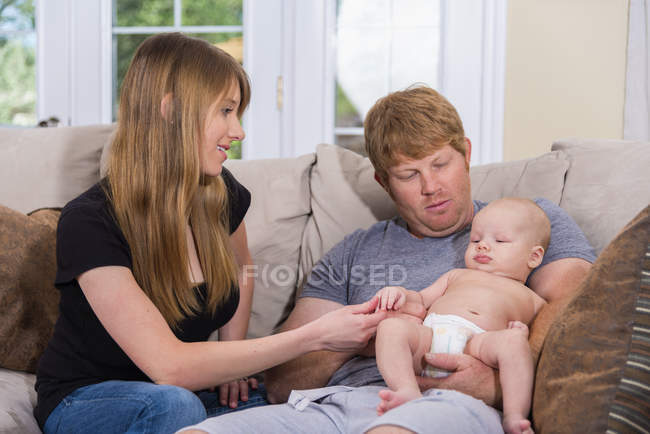 Genitori felici con bambino seduto sul divano — Foto stock