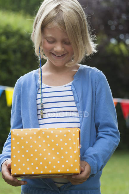 Girl holding birthday present outdoors — Stock Photo
