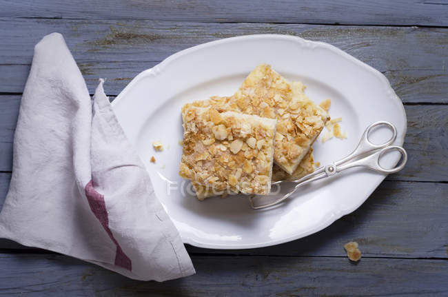 Gâteau de levure tranché avec des amandes et du sucre sur assiette sur bois — Photo de stock