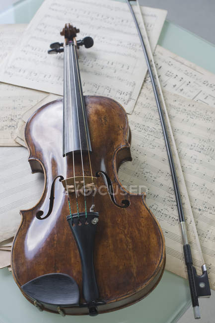 Antique violin and violin bow on musical notes — indoor, Color - Stock Photo | #181850660