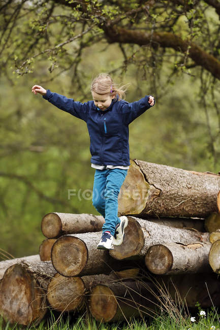 Девушка прыгает из стопки деревянных бревен — стоковое фото