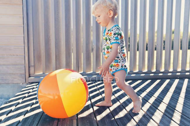 Menino correndo atrás da bola de praia — Fotografia de Stock