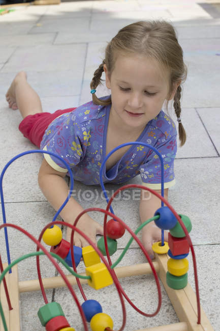 Petite fille jouant avec jouet en bois coloré — Photo de stock