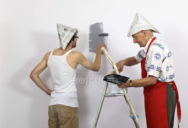 Grand-père et petit-fils portant des chapeaux en papier mur de peinture — Photo de stock