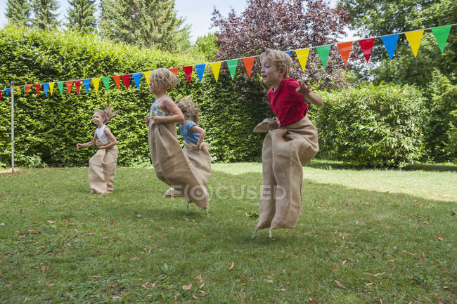 Children having a sack race in garden on a birthday party — Stock Photo