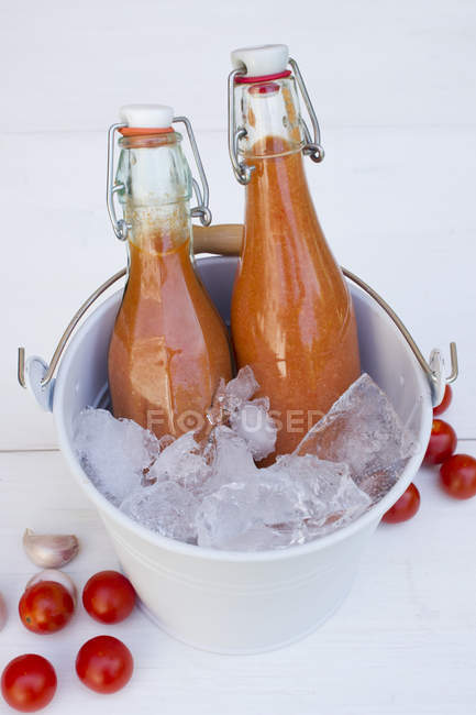 Germany, Baden Wuerttemberg, Bottled gazpacho in bucket with crushed ice — Stock Photo