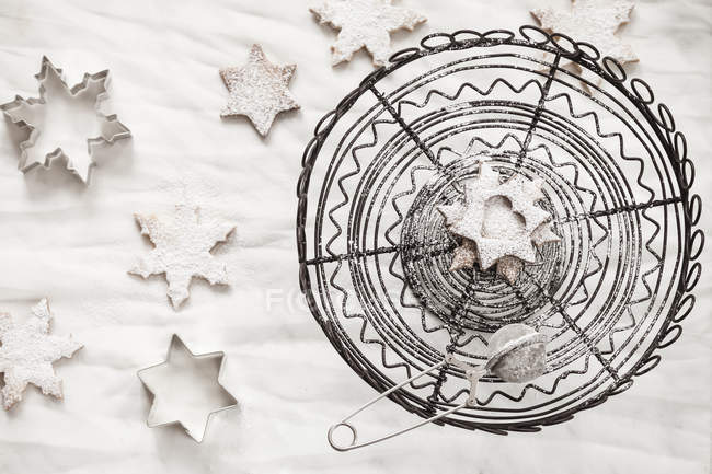 Nahaufnahme von weihnachtlich bestreuten Plätzchen mit Zucker und Sieb auf Holztisch — Stockfoto