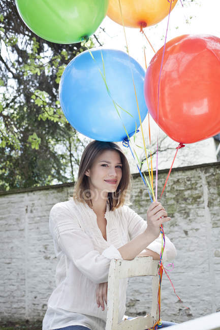 Усміхнена молода жінка тримає повітряні кулі — стокове фото