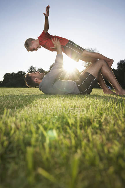 Father holding son aloft on soccer field — Stock Photo