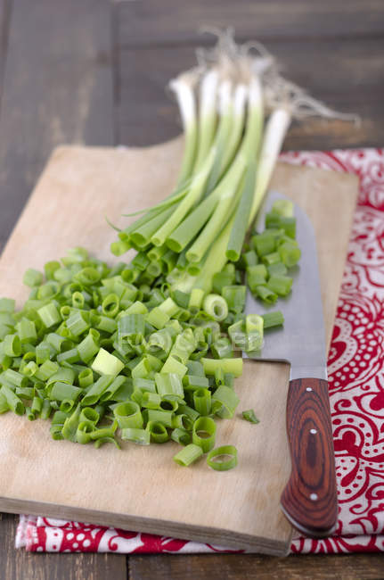 Partly chopped leek on wooden chopping board with knife — Stock Photo