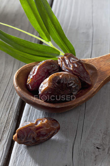 Wooden spoon with dates on wooden table, closeup — Stock Photo