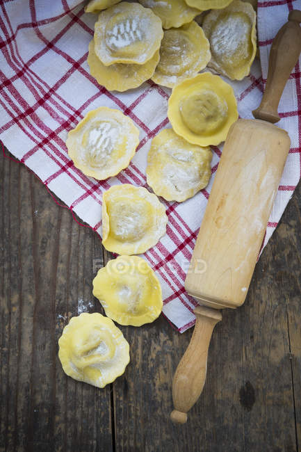 Stuffed pastry, dish towel and wooden rolling pin on wooden table — Stock Photo