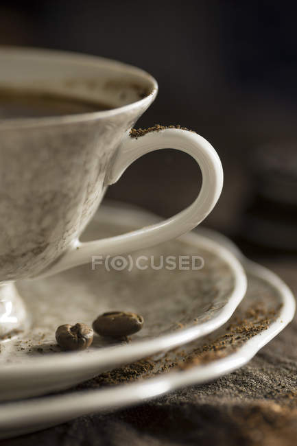 Cup of coffee and saucer with coffee beans — Stock Photo