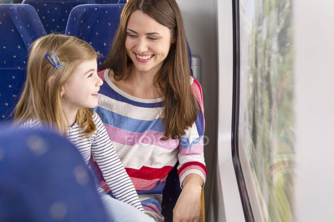 Mother with daughter traveling by train, sitting near window — Stock Photo