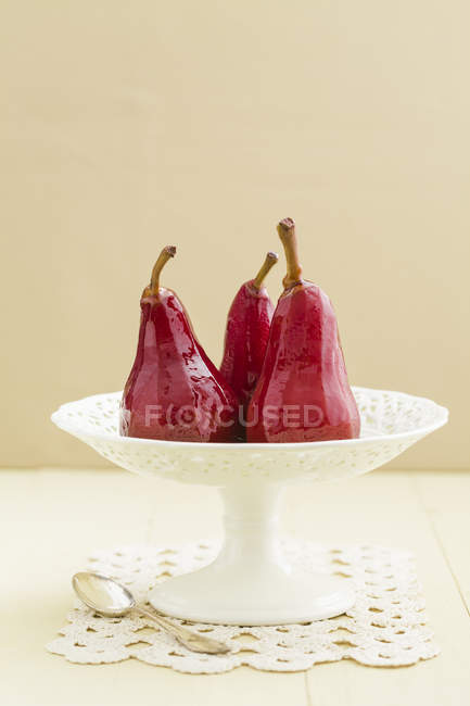 Poires pochées dans le vin rouge sur le stand de gâteau — Photo de stock
