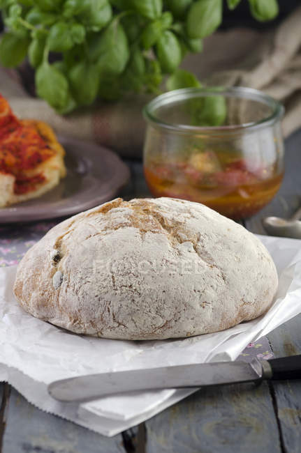 Fresh olive bread on paper with knife — Stock Photo