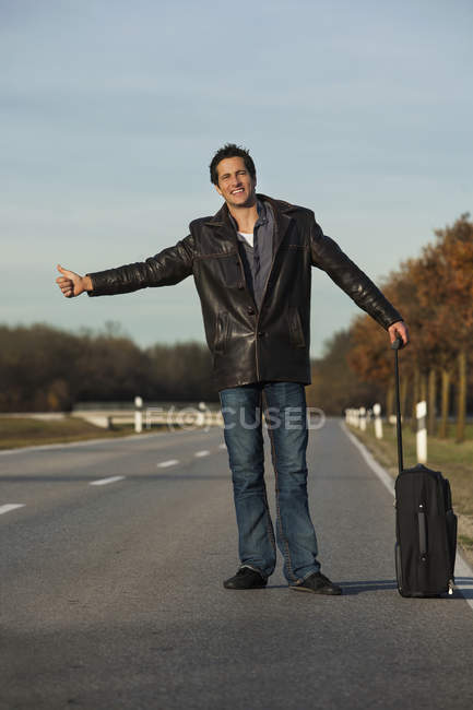 Hombre adulto haciendo autostop en la carretera - foto de stock