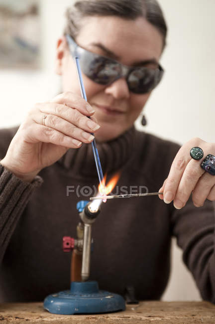 Mujer madura haciendo cuentas de vidrio durante el día - foto de stock