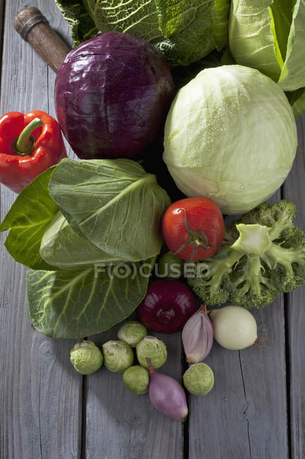 Variétés de choux et légumes sur table en bois gris — Photo de stock
