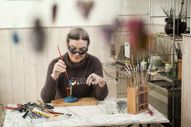Mature woman making glass beads at daytime — Stock Photo