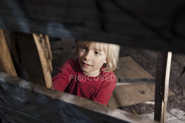 Ragazzo sorridente distogliendo lo sguardo, vista tra recinzione in legno — Foto stock