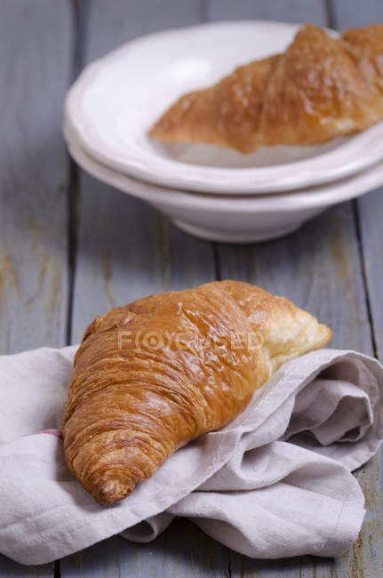 Croissants sur assiettes et serviette sur table en bois — Photo de stock