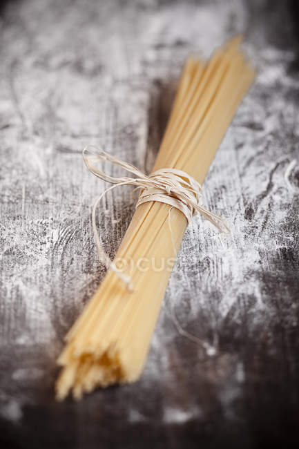 Un fascio di spaghetti su tavola di legno con farina — Foto stock