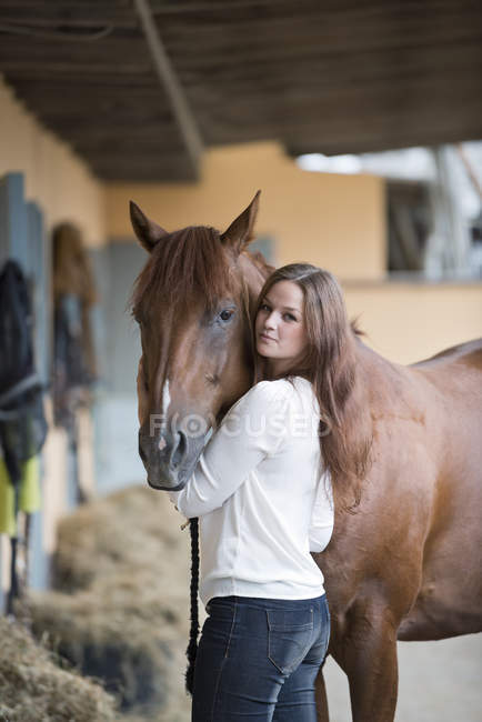 Jeune femme avec son cheval à la ferme — Photo de stock