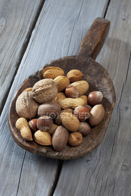 Wooden shovel with blend of nuts on wooden table — Stock Photo