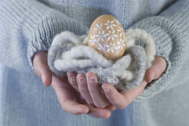 Female hands holding easter egg in wool cloth — Stock Photo