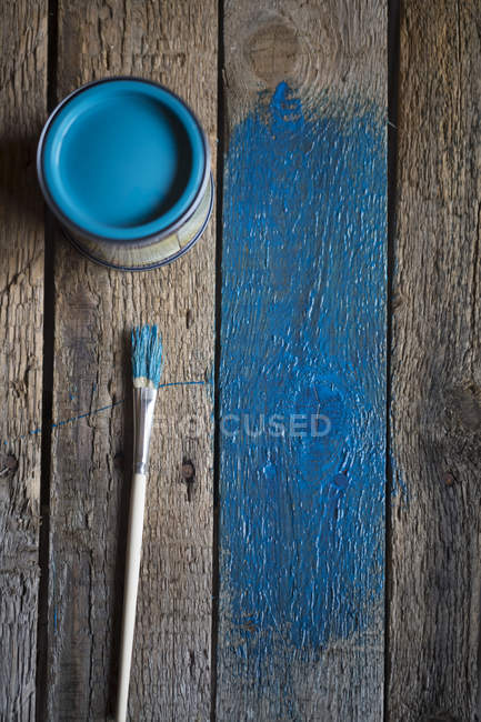Vieilles planches en bois avec pinceau, boîte à peinture et peinture bleue partielle — Photo de stock