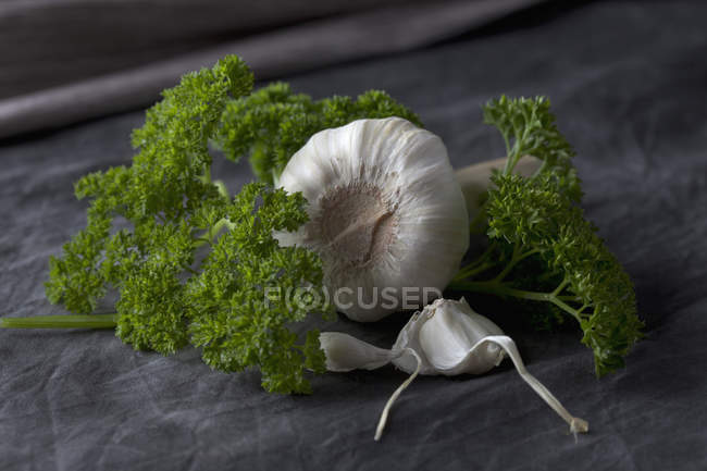 Primo piano di prezzemolo e bulbi di aglio su tessuto nero — Foto stock