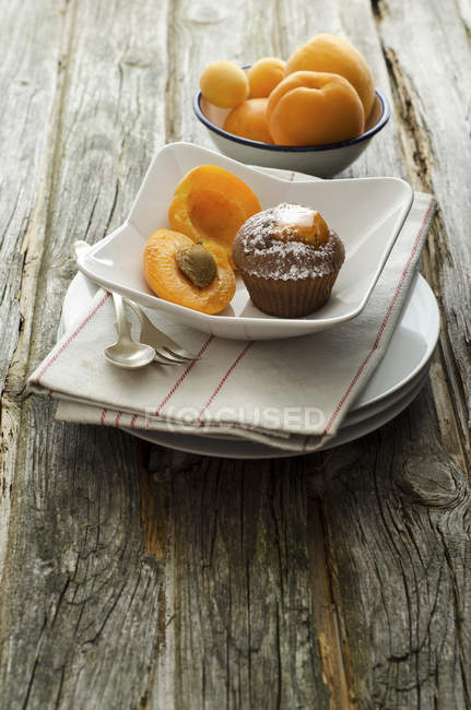 Ciotole di albicocche con muffin sul tavolo di legno, da vicino — Foto stock