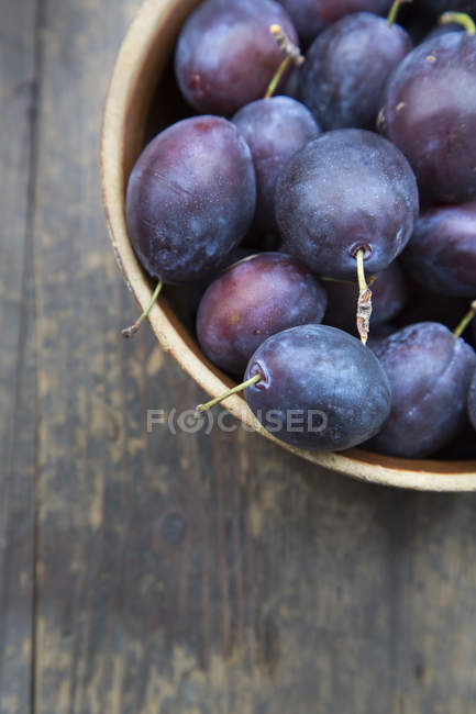 Close-up of bowl of fresh plums on wooden table — Stock Photo