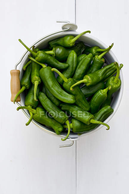 Secchio di peperoni verdi su superficie di legno bianca — Foto stock