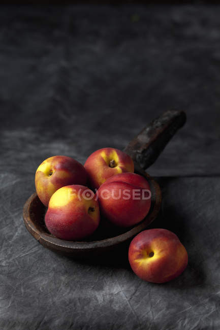 Frische Nektarinen in Holzlöffel auf schwarzem Stoff — Stockfoto