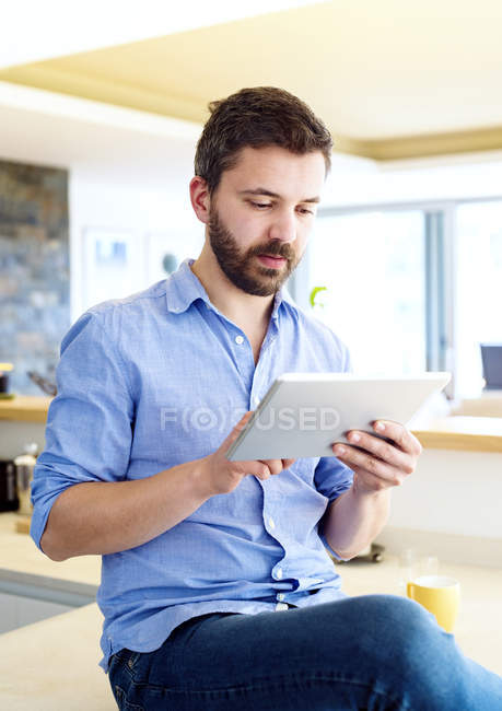 Mann arbeitet in Küche mit digitalem Tablet — Stockfoto