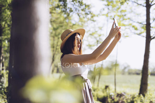 Jovem mulher tomando selfie com smartphone na natureza — Fotografia de Stock