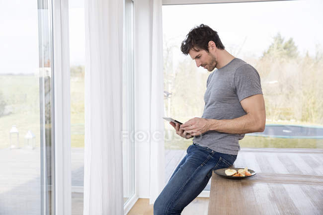 Hombre en casa usando tableta digital - foto de stock