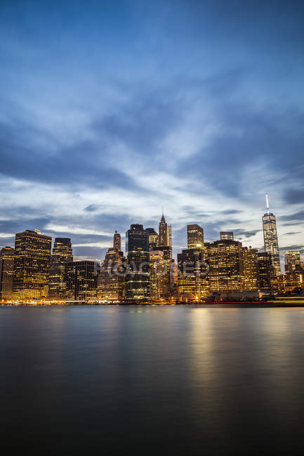 USA, New York City, view from Brooklyn to lighted Manhattan skyline and East River at evening twilight — Stock Photo