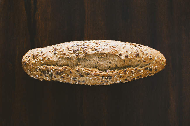 Seed homemade bread on dark wooden surface — Stock Photo